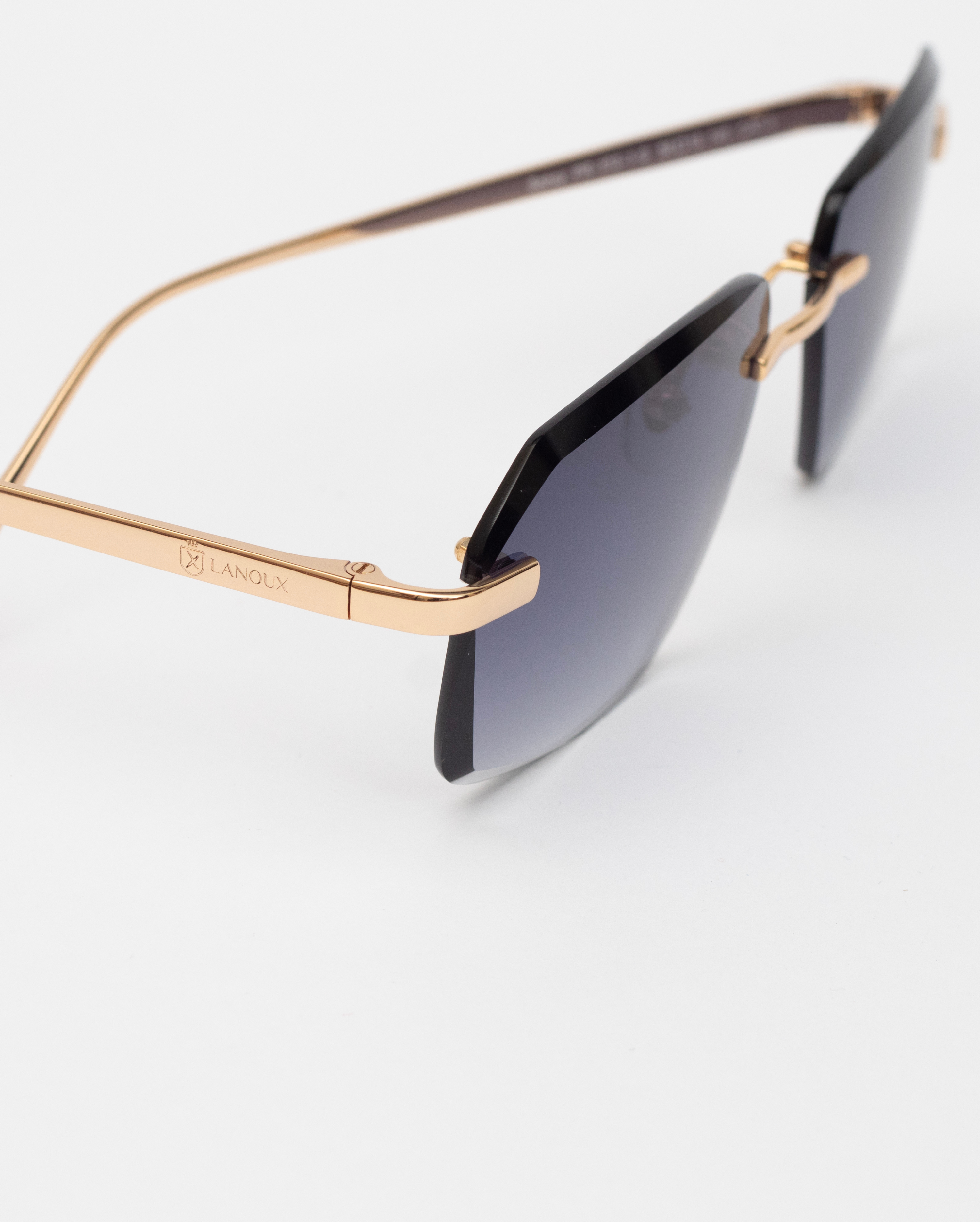 The 'Sancy' model sunglasses are designed with a blue light filter, featured in gradient grey lenses, and supported by 18k gold frames that boast a meticulous diamond cut. The side angle emphasizes the slender gold arm and the elegant Lanoux logo, all against a stark white background that enhances the glasses' sophisticated features.