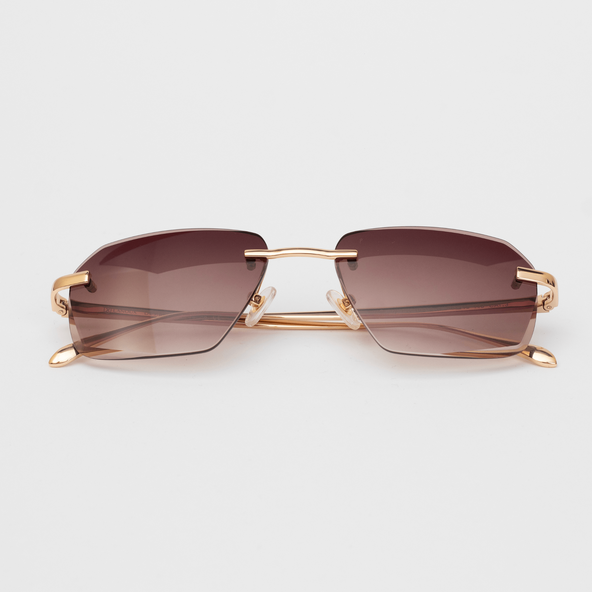 "Model Sancy sunglasses featuring a sophisticated brown gradient, diamond-cut, rimless design with elegant 18K gold hardware, showcased against a white background.