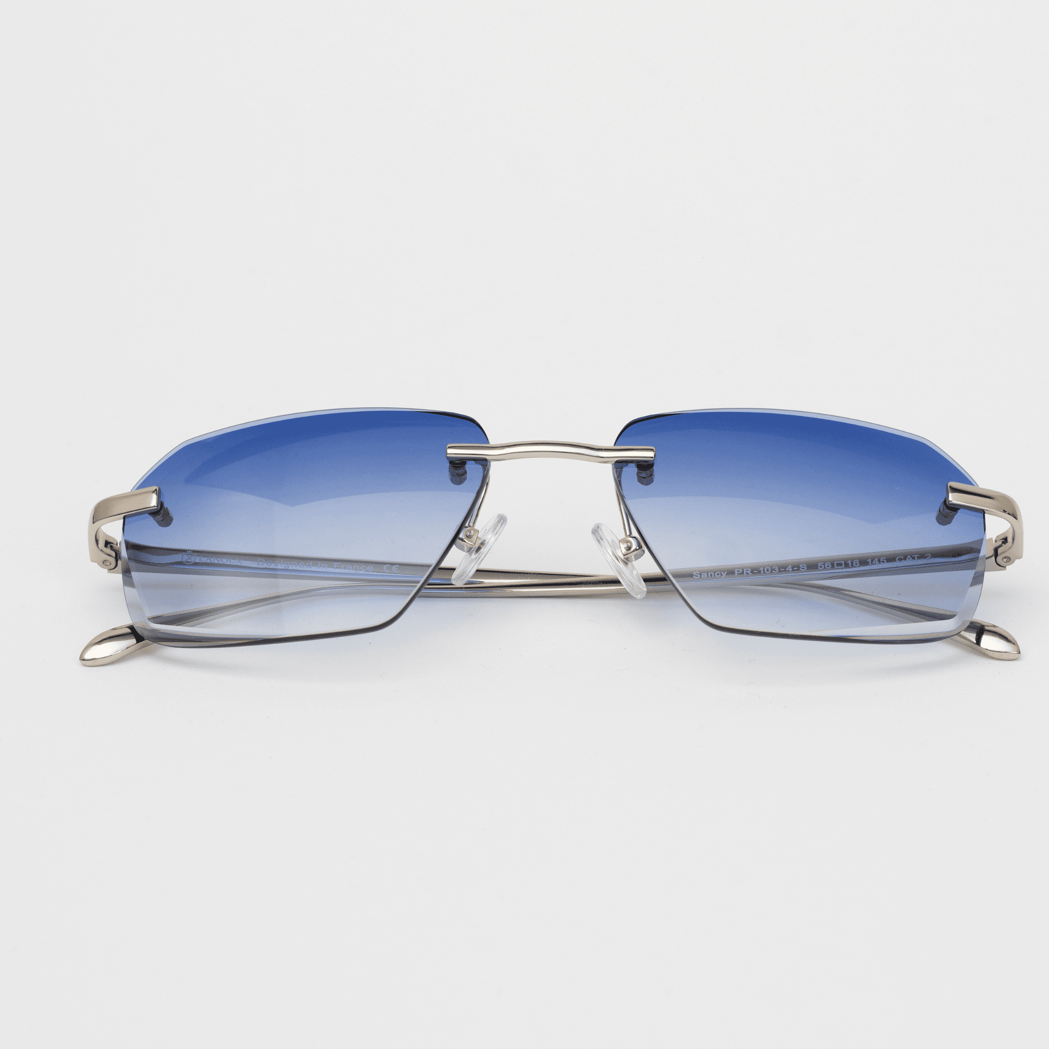 he Sancy rimless glasses feature a striking diamond cut with onyx blue lenses, held by a sleek sterling silver frame, displayed in a front-facing angle against a white background.